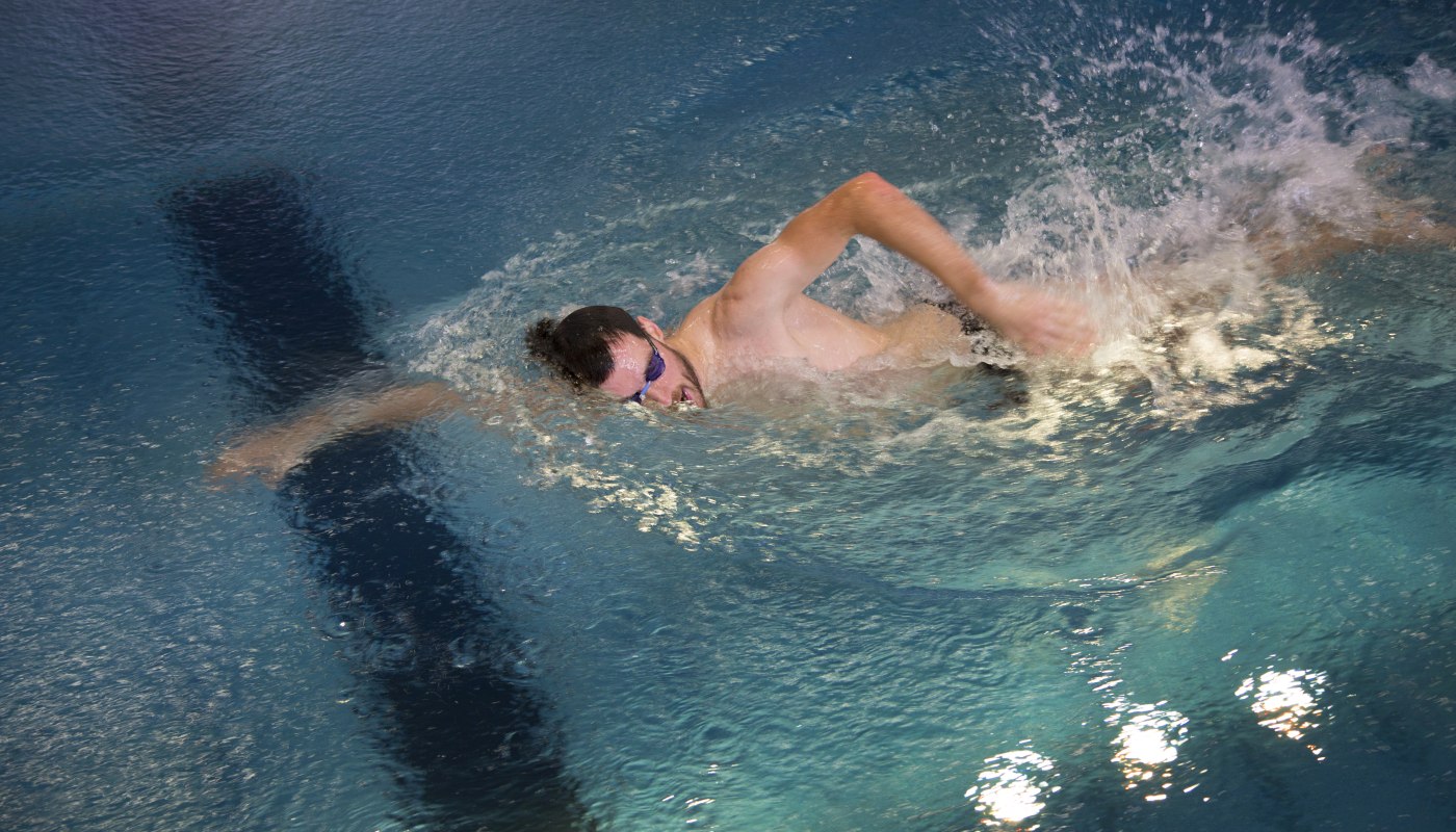 Es schwimmt ein Mann mit Schwimmbrille in einem Gegenstrompool von FlussPool.