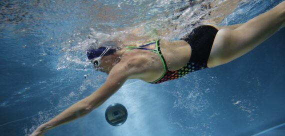 Eine Frau unter Wasser, die in einem Gegenstrompool von FlussPool schwimmt.